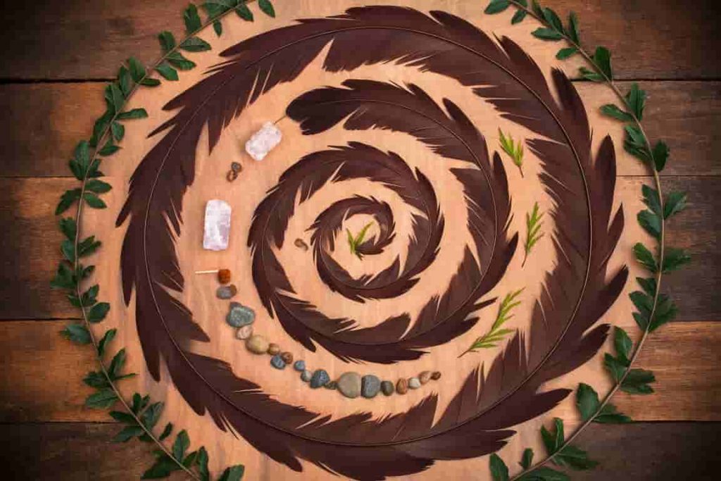 Spiral mandala of brown feathers with crystals forming an arrow, symbolizing personal and spiritual growth