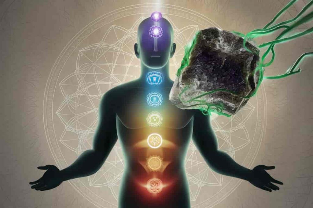 Transparent human silhouette with chakras, large green amethyst crystal connected to heart chakra