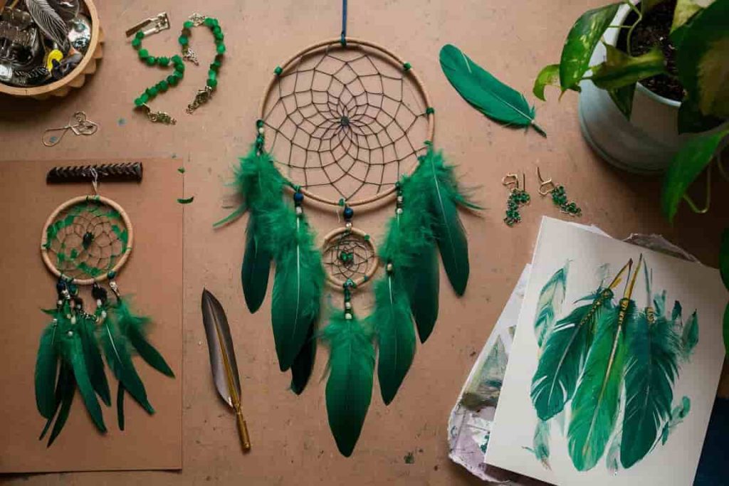 Creative projects using green feathers, including dreamcatcher, jewelry, and artwork