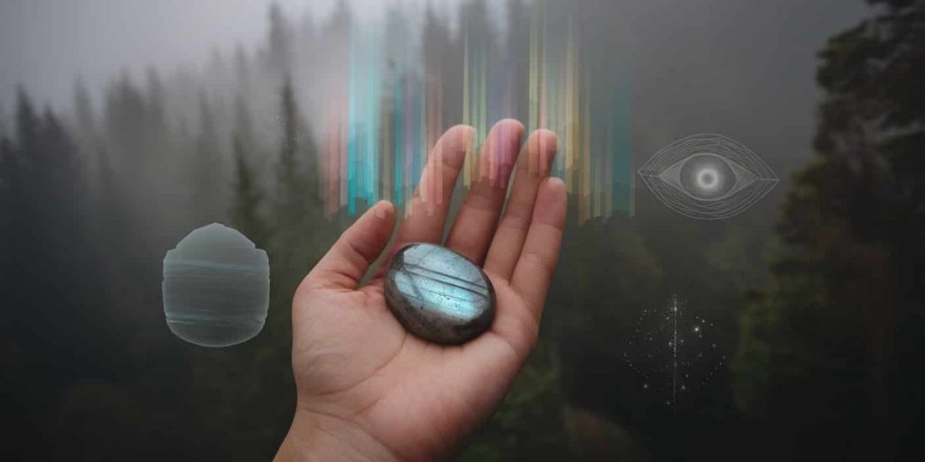 Hand holding a labradorite palm stone emitting colorful light beams, surrounded by ethereal symbols representing protection, intuition, and cosmic connection in a misty forest setting.